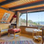 Wohnzimmer mit Holzdecke und großem Fenster zum See