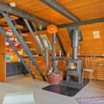 Wohnraum mit Kamin, Holzwand und Treppe zur oberen Etage.