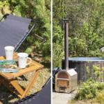 Outdoor area with lounge chair, table, book, and mugs. Wooden hot tub with stove and grill in garden.
