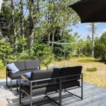Deck with seating group, umbrella, and lounge chairs in green area.