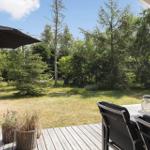 Deck with table, chairs, and umbrella. Lawn and trees in the background.