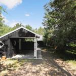 Black wooden carport with open front and plant in front