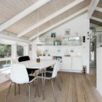 Dining area with white table, chairs, and wooden floor under a wooden ceiling