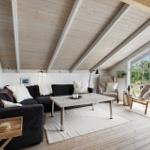 Living room with sofa, table, and chair under wooden ceiling with garden view.