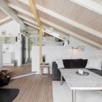Living area with fireplace, sofa, and dining table under wooden ceiling.