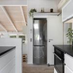 Kitchen with white cabinets, black countertops, and stainless steel refrigerator.