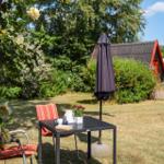 Black wooden house with terrace and garden. Red window frames. Rear yard with seating area.