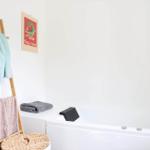 Badezimmer mit Dusche, Waschmaschine und Waschtisch mit Spiegel.