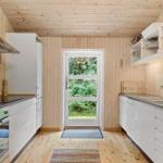 Kitchen with white cabinets, wooden walls, and door to the garden.