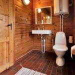 Dusche mit Glaswand, weißen Fliesen und Holzwand. Fenster und Tür sichtbar.