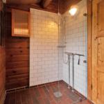 Schlafzimmer mit Holzwand und Fenster. Bett mit Bettwäsche und Decke.