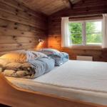 Zwei Betten in einem holzverkleideten Raum mit Fenster und Heizung.