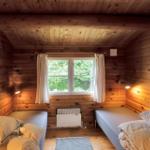 Schlafzimmer mit Holzwand, Fenster, Bett und Küchenzeile.