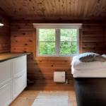 Zimmer mit zwei Betten, Holzwänden und Fenster mit Blick auf Grün.