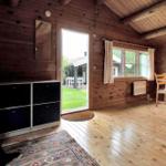Esszimmer mit Holztisch, Stühlen und Wandbild. Holzwände und Fenster mit Blick nach draußen.