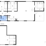 Wohnzimmer mit Holzwand, Sofa, Tisch, Teppich und Fernseher.