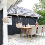 Terrasse mit Holztisch und Stühlen, schwarze Wand, Fenster und Dach
