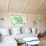 Ein Raum mit Holzwand und -decke, großem Fenster, Sofa, Tisch und Küchenutensilien.