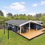 Ein modernes Haus mit Terrasse und Garten. Ein Schaukeln und eine Hängematte sind im Garten vorhanden.