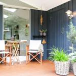 Terrasse mit Tisch, Stühlen und Sonnenblumen. Im Hintergrund steht ein Holzgestell mit Hängemöbel.