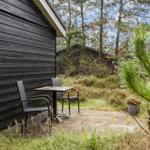 Outdoor area with table and two chairs in front of a wooden cabin in the woods.