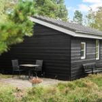 Black wooden cabin with white windows and terrace in the woods