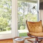 Wall art with landscape and text Alletiders Odsherred next to window with garden view.
