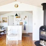 Kitchen with white cabinets and wooden floor. Black wood stove stands in the room.