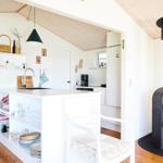 Living kitchen with wooden floor, TV, chairs, and windows to the garden.