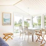 Dining area with white table and chairs, large windows, and a pendant light.