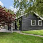 Ein dunkles Holzhaus mit Gartentor und Sitzbank im Vorgarten.
