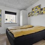 Schlafzimmer mit Doppelbett, zwei Nachttischen und Fenster mit Pflanze.