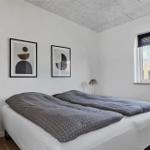 Zwei Betten mit grünen Decken stehen in einem Raum mit Fenster und Wandbildern.