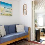 Wohnzimmer mit Sofa, Sessel und Bücherregal an der Wand.