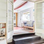 Wohnzimmer mit Sofa, Sessel, Bücherregal und Fenster.