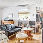 Holzschrank mit Plattenspieler, Lampe und Poster an der Wand. Gitarre lehnt an die Wand.