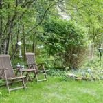 Garten mit Holzschaukel, Laterne und Skulptur unter Bäumen.