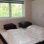 Schlafzimmer mit Bett, Stuhl und Hochstuhl. Holzwände und Fensterblick auf Gras.