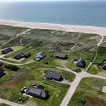 Aerial view of coastal houses with sandy beach and dunes.