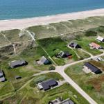 Aerial view of beachside houses on green dunes near the sea.