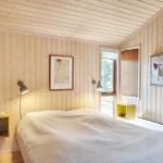 Zimmer mit Holzwand, zwei Betten, Wandlampe und Bild an der Wand.