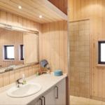 Bad mit Dusche, Waschbecken und Spiegel an Holzwand