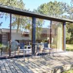 Haus mit Terrasse, Sitzbank und Sonnenschirm unter Bäumen.