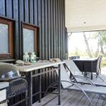 Ein dunkelholzverkleidetes Ferienhaus mit Terrasse, Garten und Bäumen im Hintergrund.