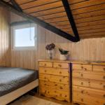 Schlafzimmer mit Holzwand, Bett und Doppelbett. Holzdecke mit Trägern.