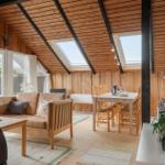 Haus mit Terrasse, Garten und Schaukel. Weiße Bank und Stühle auf Holzterrasse.