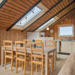 Esstisch mit Stühlen, Kaffeekanne und Brot im Holzhaus mit Dachfenster.