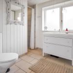 Badezimmer mit Toilette, Dusche und Spiegel im weißen Holzdesign.