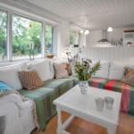 Ein Esszimmer mit weißem Tisch, Stühlen und Kamin. Durch große Fenster ist eine Terrasse sichtbar.