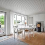Küche mit weißen Schränken, Holzoberflächen und Fensterblick auf Grün.